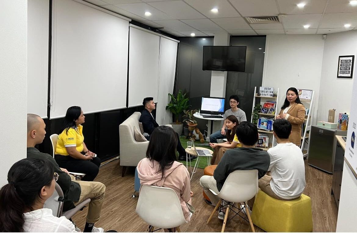 Candidates seated in a circle listening to a consultant at an information session